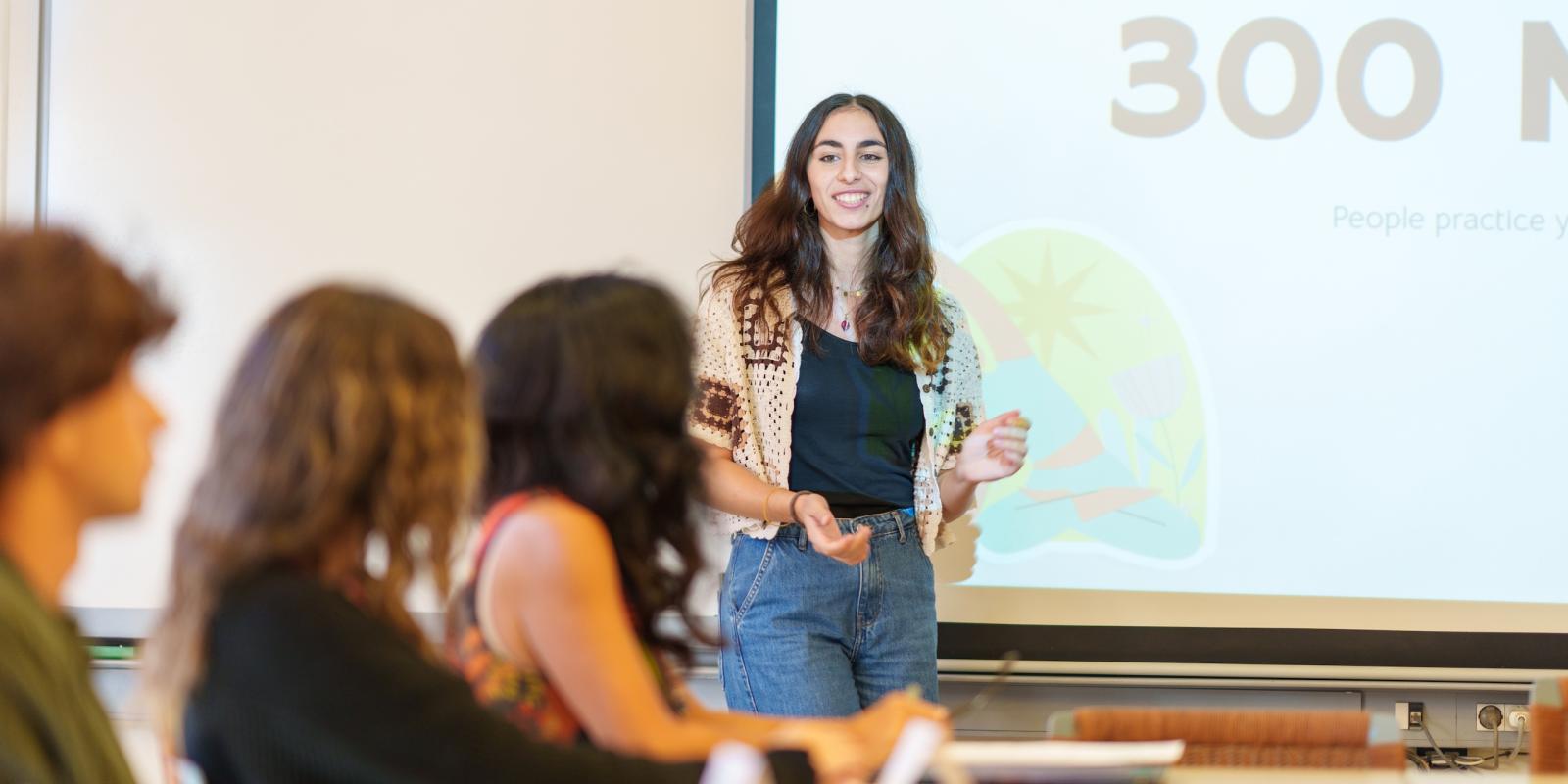 a girl giving a presentation to her peers in a classroom
