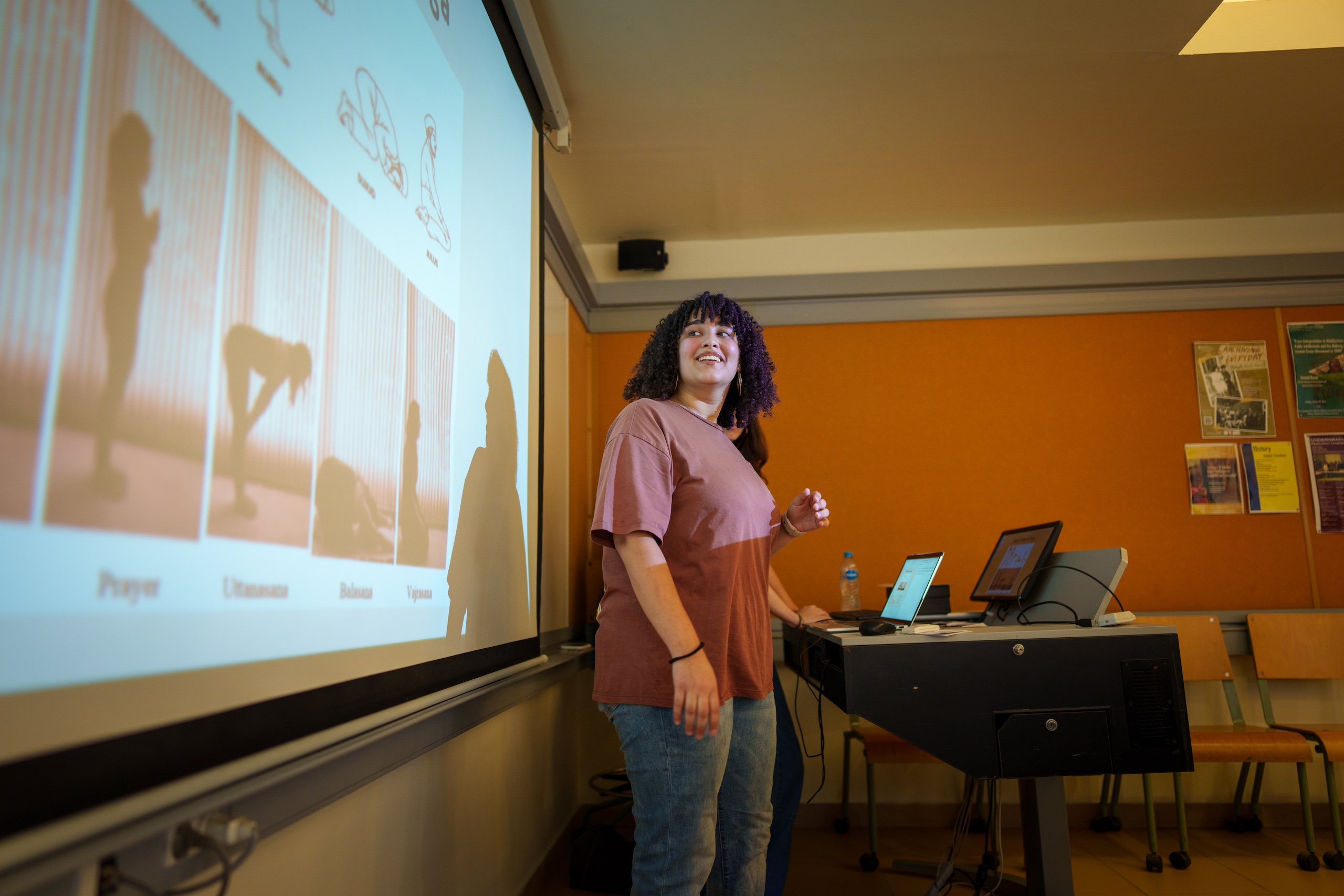 a girl with black curly hair giving a presentation in a classroom