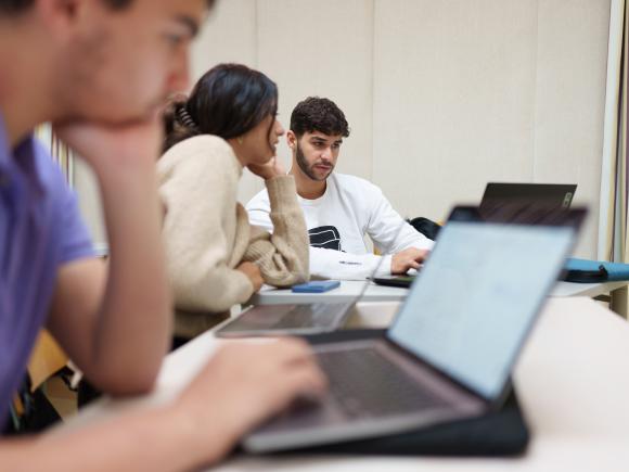 a student sitting in a classroom working on a laptop