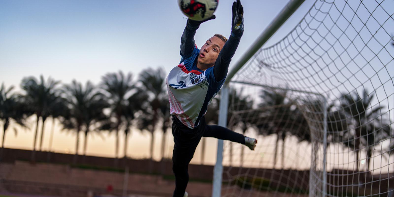 a goal keeper jumping to catch the ball