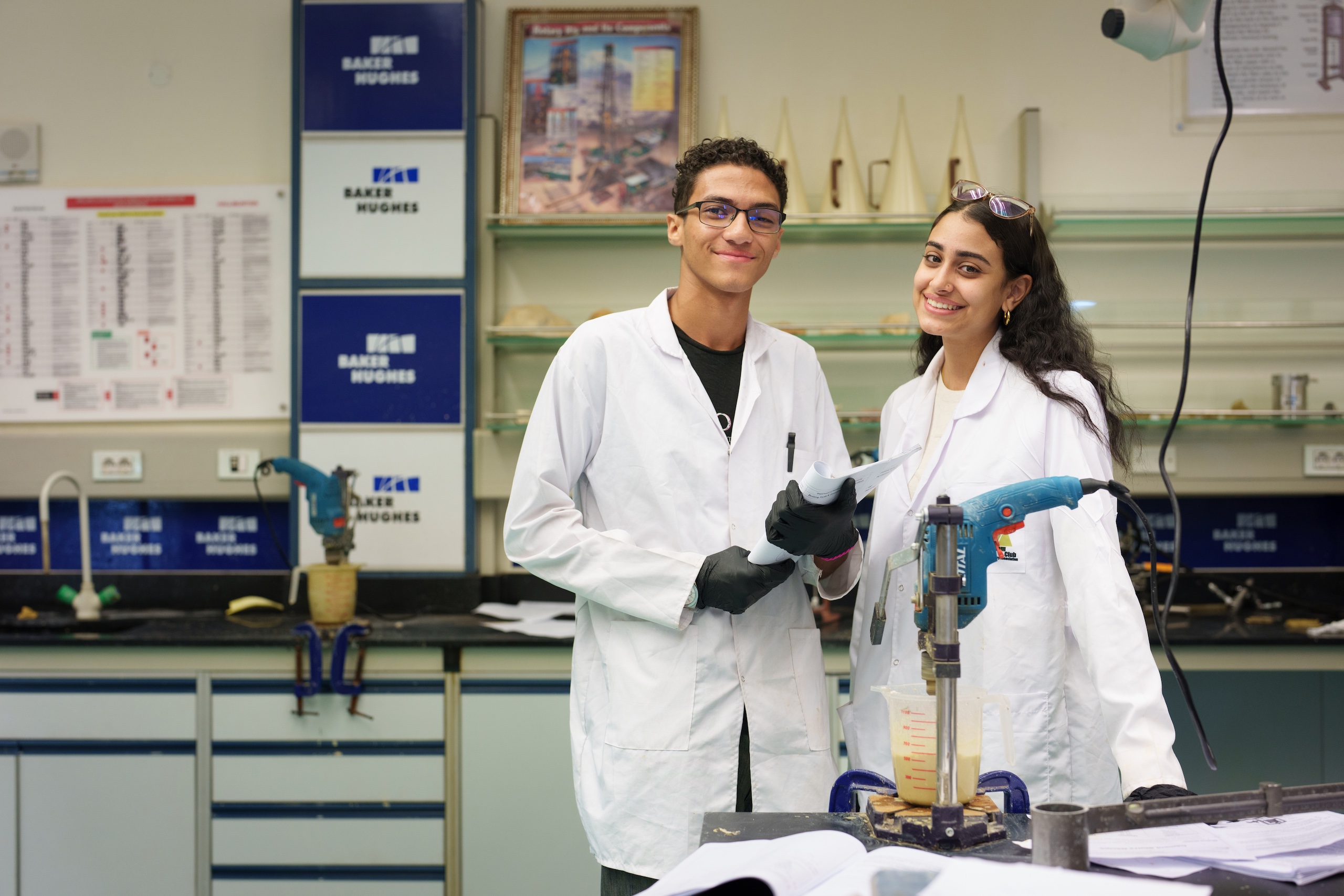 two girls wearing white coats in a lab room
