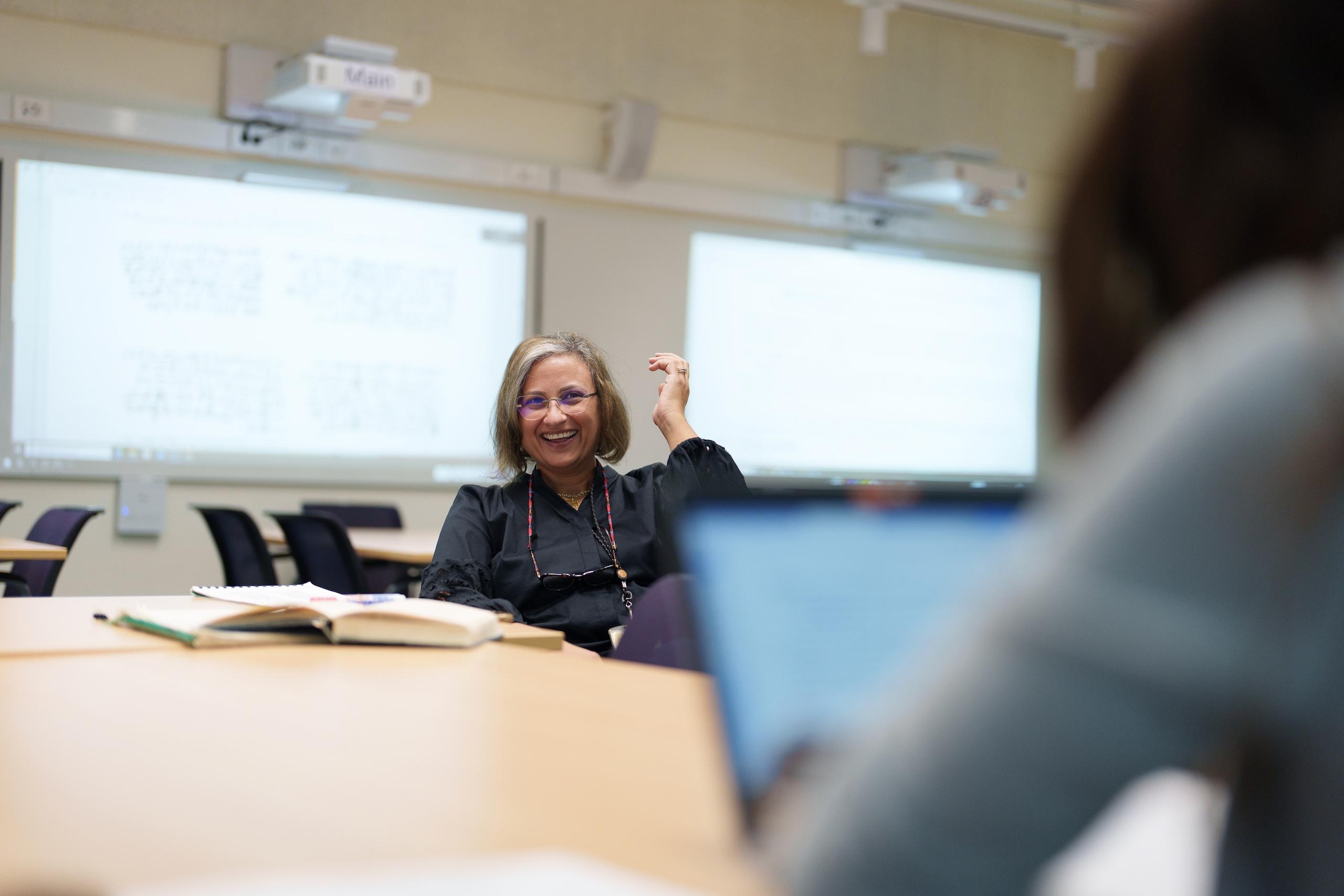 a faculty member with short blond hair sitting in a classroom smiling