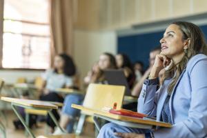 Lady wearing a suit with her hand on her chin in a classroom