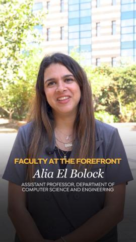 A woman is standing and smiling. Text: Faculty at the Forefront Alia El Bolock, Assistant Professor, Department of Computer Science and Engineering