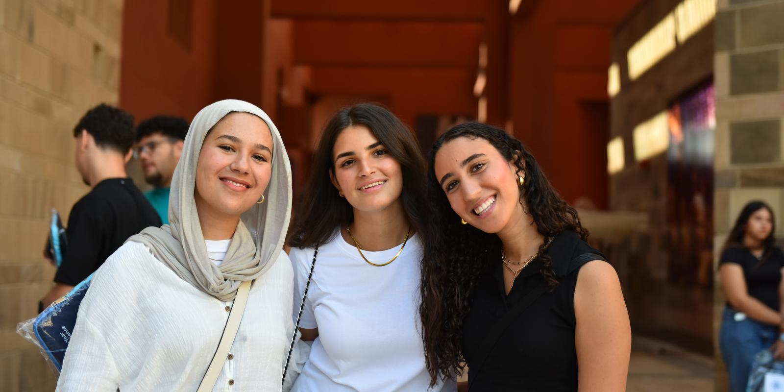 three girls standing together taking a group photo a smiling