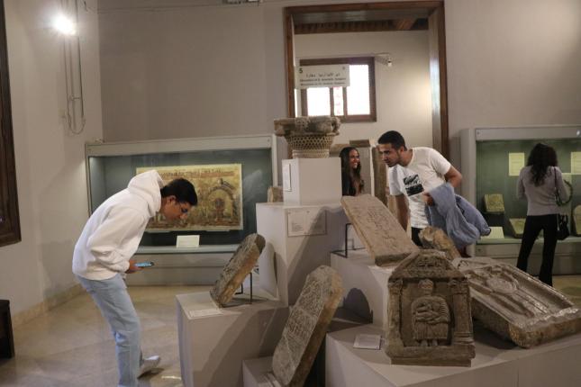 Students bending down and standing in front of Coptic monuments to examine them
