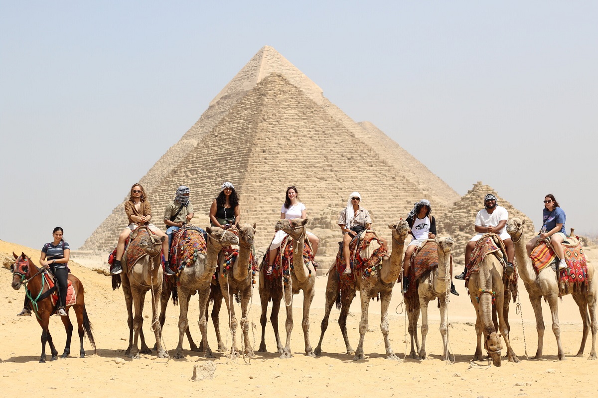 International students riding camels in front of the Pyramids