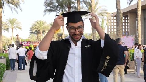 A male is wearing his cap and gown and smiling