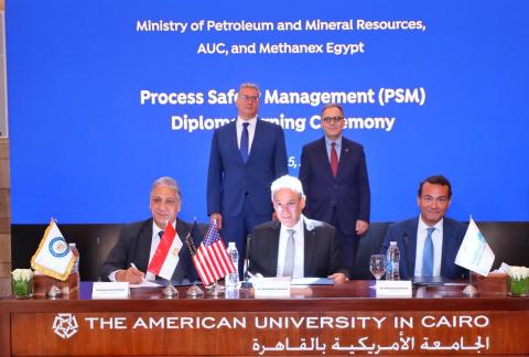 Senior officials from AUC, including the president and provost, sit and stand at a table to sign a memorandum of understanding.