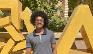 Ahmed Amara stands in front of a sign that reads AUC